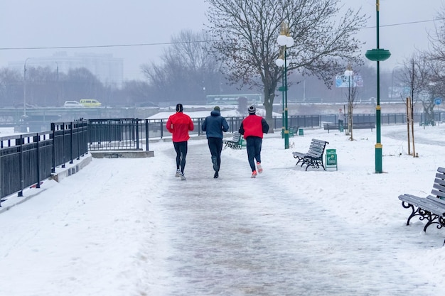 A group of men athletes goes for a morning run in a winter park