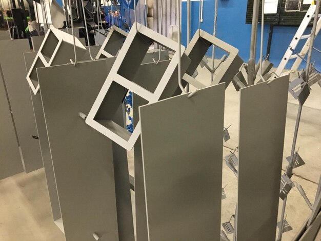 A group of metal pieces are hanging in a room with a blue wall behind them.