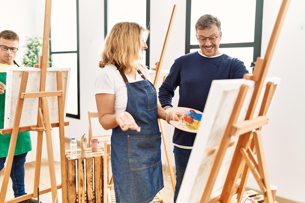 Group of middle age paint students drawing at art studio. Teacher looking student draw.