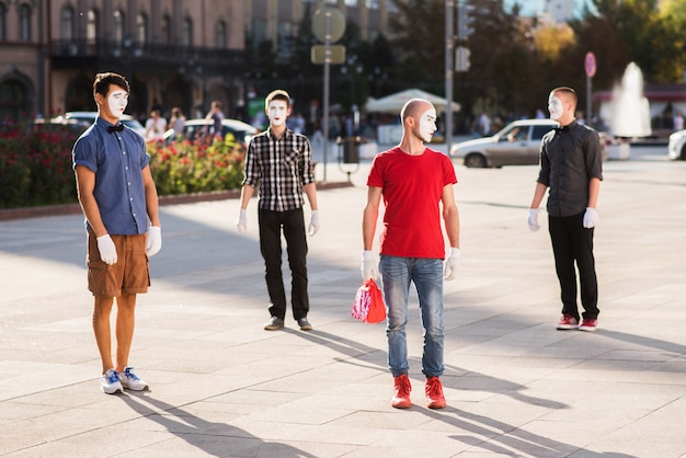 A group of mimes posing in the city center for a photo