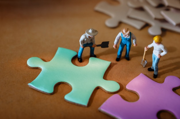 Group of Miniature Worker Working on Jigsaw Puzzle