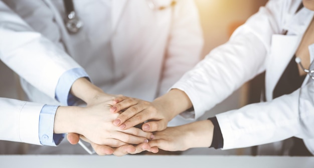 Group of modern doctors joining hands as a circle. Teamwork in medicine during Coronavirus pandemic, covid 2019.