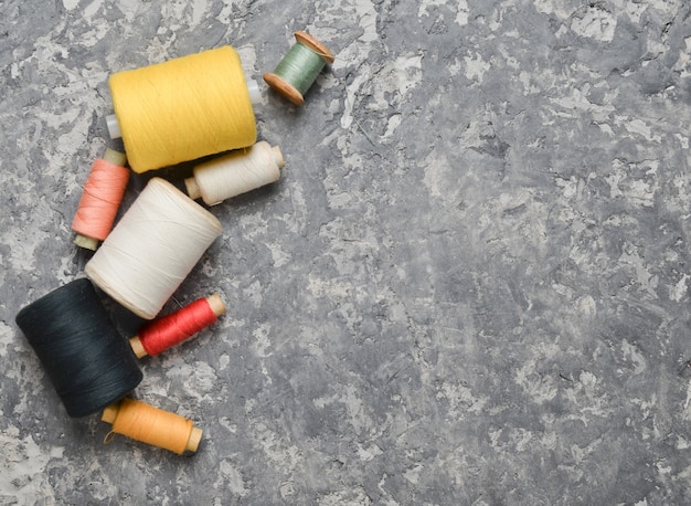 A group of multicolored skeins of thread on a gray concrete background. The concept of needlework. Made hand sewing clothes.