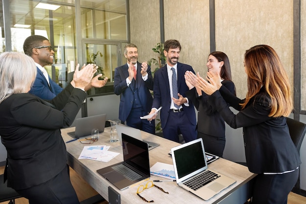 Group of multiethnic colleagues clapping hands in office