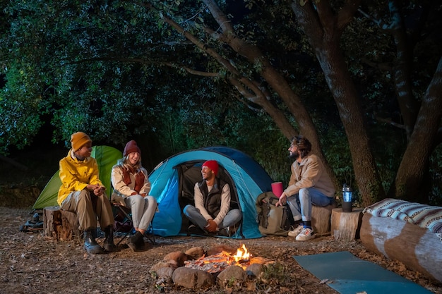 Group of multiethnic friends happy around the bonfire camping hike trekkers excursion in the nature