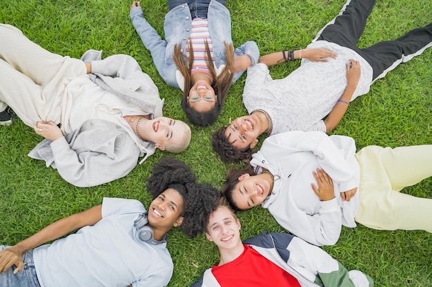 Group of multiethnic friends laying down in a circle on the grass in the park Friendly youth