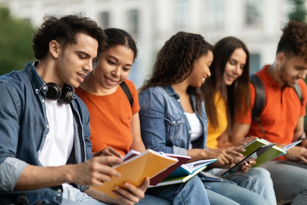 Group of multiethnic students with books study together outdoors