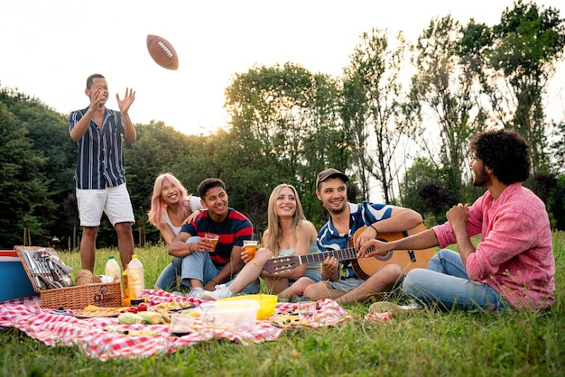 Group of multiethnic teenagers spending time outdoor on a picnic at the park