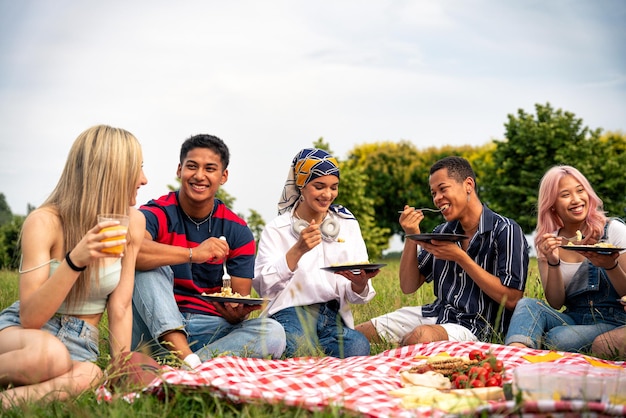 Group of multiethnic teenagers spending time outdoor on a picnic at the park