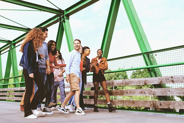 A group of multiracial young people walking together crossing a bridge on a beautiful weekend