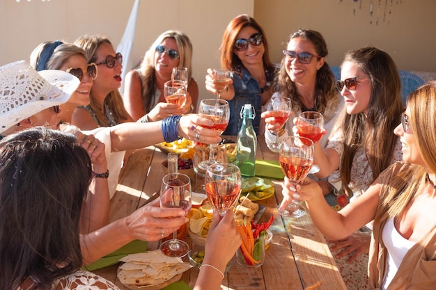 Group of nine people celebrate a birthday Smiling women with red wineglass wooden table food and drink Friendship concept