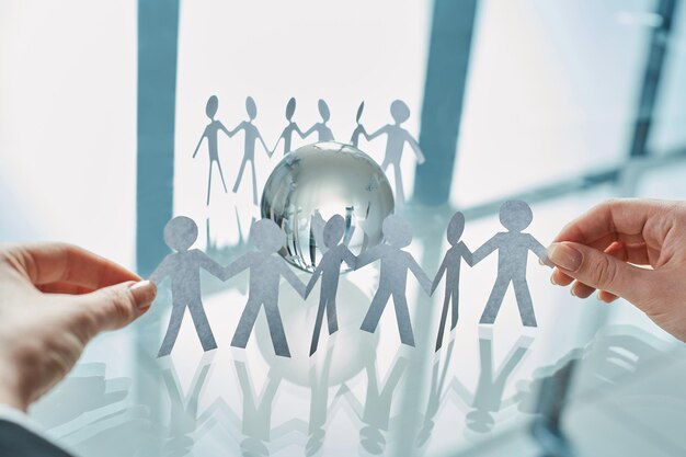 Group of paper people near a glass globe