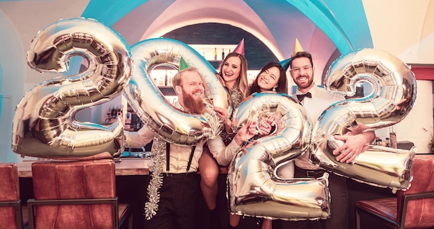 Group of party people celebrating the arrival of 2022, men and women looking into camera