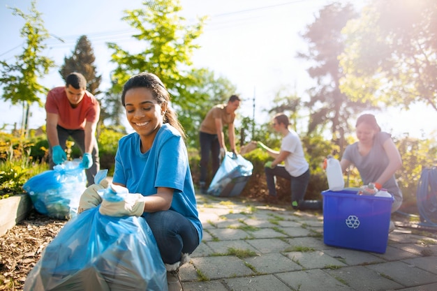 Photo a group of people are cleaning the garden with a blue container