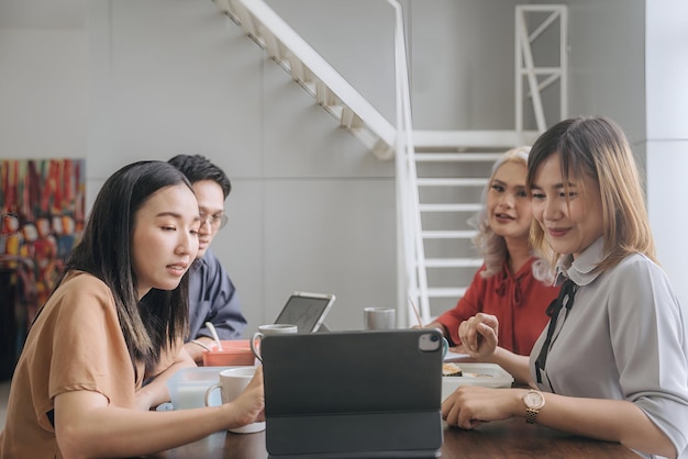 a group of people are sitting around a laptop and one of them has a camera on it