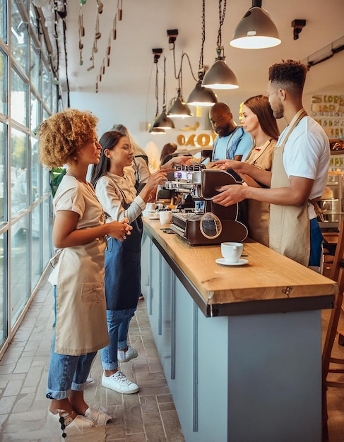 a group of people are standing at a counter with a coffee machine in front of them