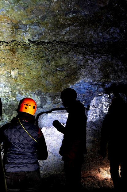 Photo a group of people are standing in a dark cave