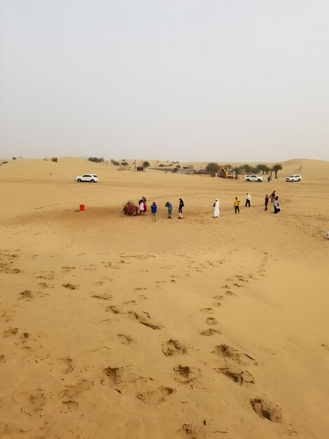 a group of people are standing in the desert with a jeep in the background