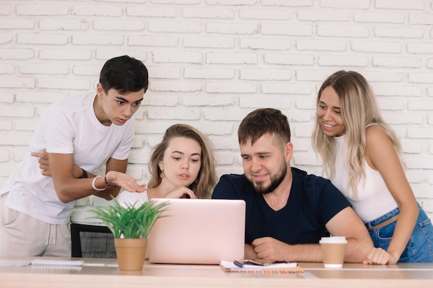 Group of people around laptop discussing work sitting in the office. Group of students study online