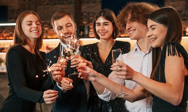 Group of people in beautiful elegant clothes are celebrating New Year indoors together