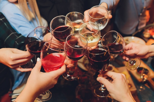 group of people clinking glasses with wine or champagne