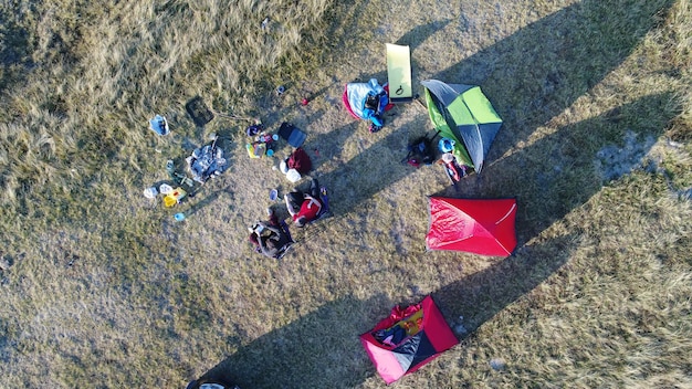 Group of people enjoying tent camping in mountains (aerial view, car not recognizable)