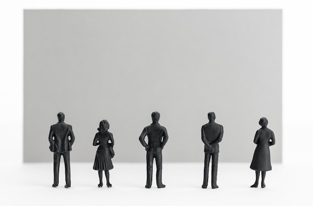 Group of people figurines looking at a blank sign Template Copy space