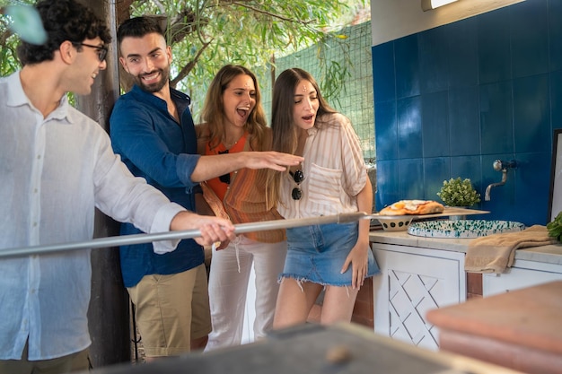 Group of people having fun cooking pizza outdoors. Friends gathering for a pizza party.