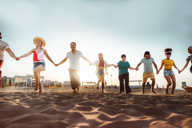 Group of people holding hands running on the beach together