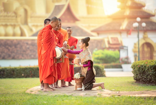 A group of people in orange robes are gathered around a monk.