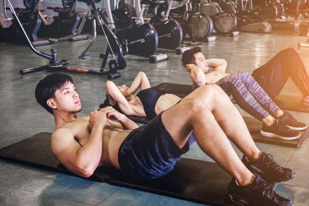 Group of people performing sit up exercises muscles at fitness training in gym