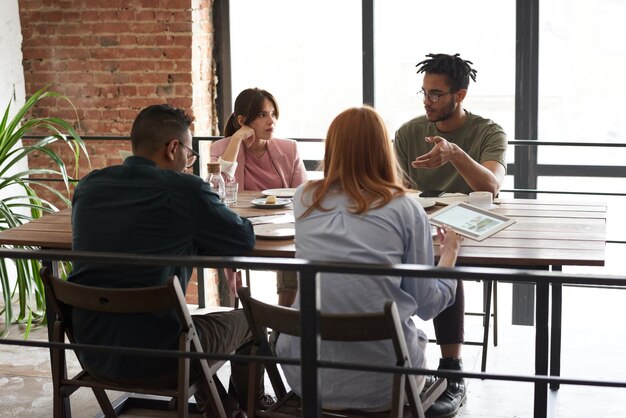 a group of people sit around a table with a menu and a man with a black shirt on