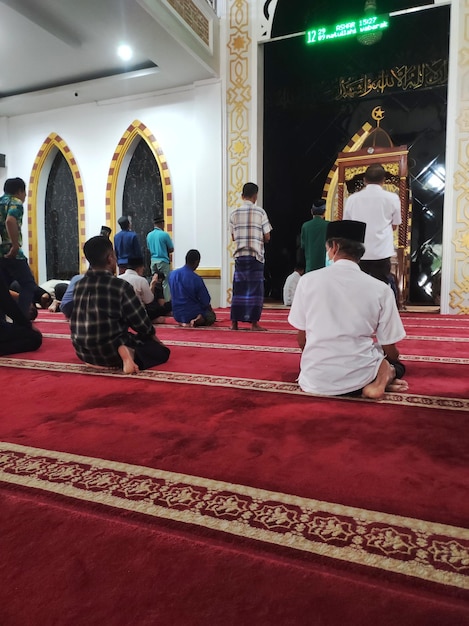 a group of people sit on a red carpet in a temple