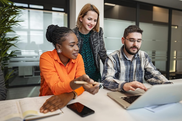 Group of people sitting around a table looking at a laptop