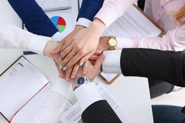 Group of people in suits crossed hands in pile