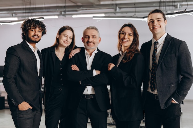 A group of people in suits stand in a room with a whiteboard behind them.