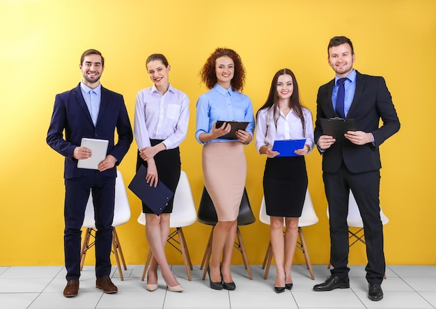 Group of people waiting for job interview on yellow wall background