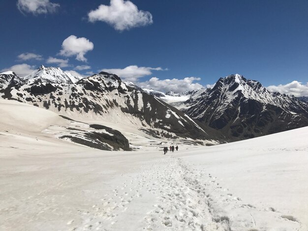 Photo a group of people walking in the snow with mountains in the background