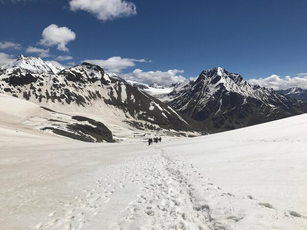 Photo a group of people walking in the snow with mountains in the background