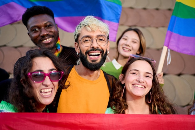 A group of people with smiling faces holding rainbow flags for a fun photograph