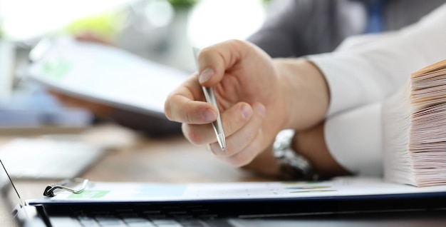 Group of people working with financial reports clipped to pad at workplace