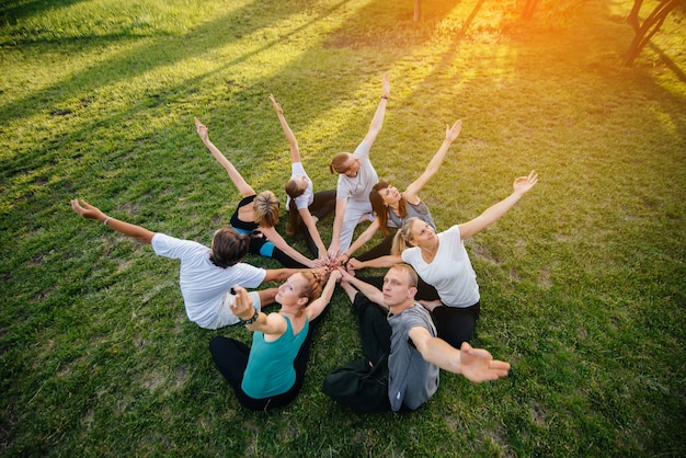 Photo a group of people do yoga in a circle in the open air during sunset. healthy lifestyle, meditation and wellness.