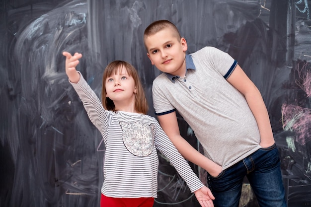 group portrait of happy childrens boy and little girl standing in front of black chalkboard