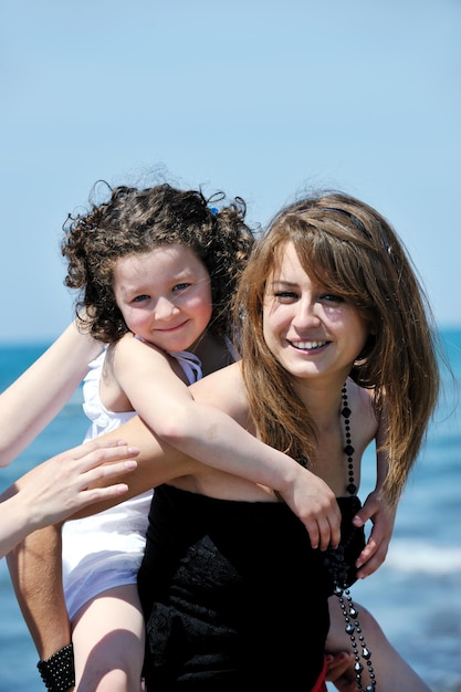 group portrait of happy childrens with young female  teacher on beach