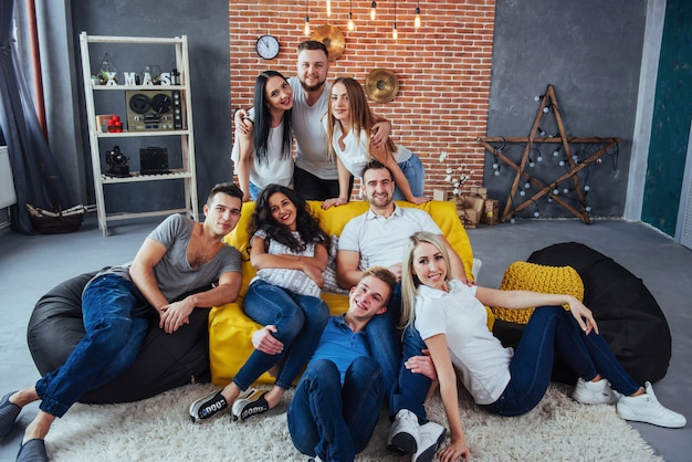 Group portrait of multi-ethnic boys and girls with colorful fashionable clothes holding friend posing on a brick wall, Urban style people having fun, s about youth togetherness lifestyle