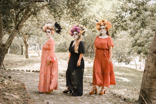 Group portrait of three women with the makeup of the catrinas. Makeup for day of the dead.