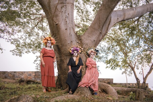 Group portrait of three women with the makeup of the catrinas. Makeup for day of the dead.