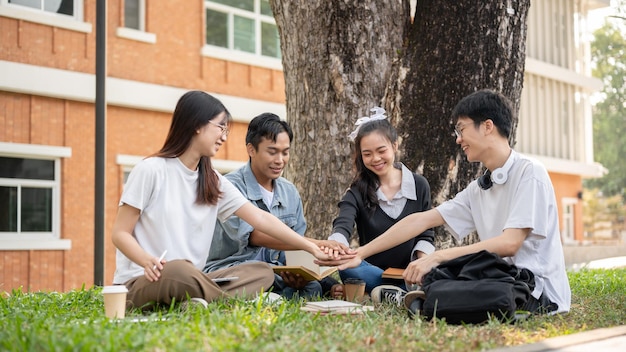 A group of positive Asian college students are putting their hands together encouraging each other