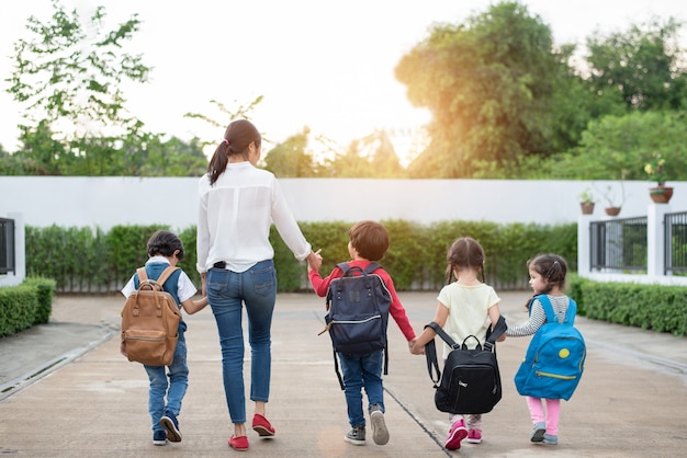 Group of preschool student and teacher holding hands and walking to home.