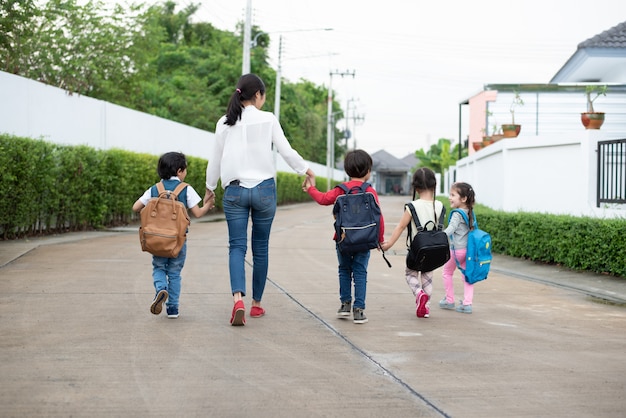 Group of preschool student and teacher holding hands and walking to home